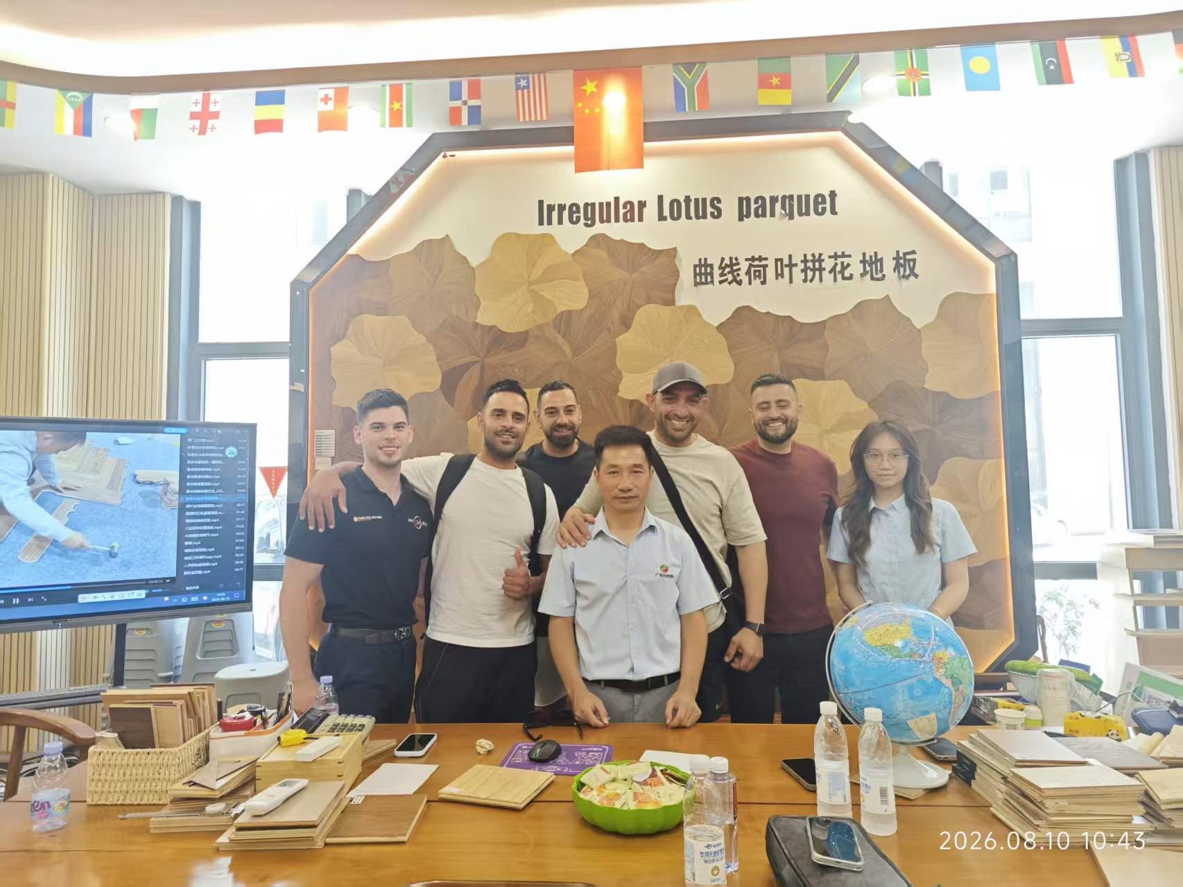 The team with a factory owner in front of a parquet flooring display